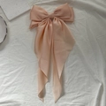 Elegant champagne pink oversized satin bow hair clip with long flowing ribbon streamers - Nude Pink
