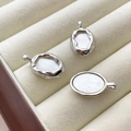 Close-up of three irregular oval silver pendants with white mother of pearl inlay - Silver Plated Border White Shell