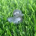 Polished grey natural stone duck figurine on green grass background - Labradorite