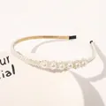 Detail of elegant pearl headband with gold metal frame and white pearls on ceramic tray - Six Flowers