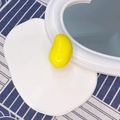 Dettaglio di un fermaglio per capelli a forma di mango giallo lucido su vassoio e tessuto - Mango Giallo