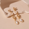 Dettaglio macro di orecchini vintage dorati con perle marquise e cristalli di zircone lucidi - Orecchini a pendente con nappe ovali di perle dorate