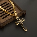 Detail eines gold-schwarzen Kreuzanhängers mit Zirkonia auf einem rustikalen Holztablett - Mit Halskette / Schwarz & Gold
