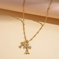 Gros plan du pendentif double croix plaqué or 18k avec strass et chaîne torsadée - Doré