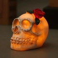 Macro shot of a resin skull LED lamp with a red rose top and warm orange light glow - Red Rose on Head Style