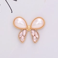 Macro shot of gold butterfly charm with teardrop pearls and pink marquise rhinestones - D1377 Pearl Bowknot Gold