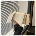 Detail of a creamy white geometric chain bag with a triangular flap and silver metal strap - White