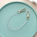 Close-up of a clear beaded strap with gold lobster clasps in a decorative tray - K178 Crystal Hand Chain
