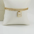Detalle de pulsera de doble cadena dorada con colgante de letra M e incrustación - Letra M