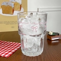 Minimalist glass cup with pink bow patterns and ice cubes on a cozy wooden table - 380ml