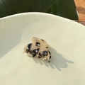 Close-up of tortoise shell mini hair claw with sparkling rhinestones in a ceramic bowl - Marble Brown
