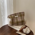 Detail van tweed ruitjes make-up tasje met rits en logo op een houten tafeloppervlak - Paars Groene Grote Ruit