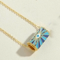 Detailed view of cylindrical gold evil eye pendant necklace with blue enamel on beige surface - Royal Blue Pendant (XL2685-6)