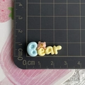 Macro shot showing 2.5cm colorful resin bear letter charm on a metric cutting mat - Yellow Bear