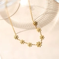 Close-up of 18k gold daisy flower necklace with elegant light shadows on a beige background - Gold Daisy Necklace
