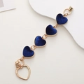 Detailed view of DIY phone charm with dark blue plush heart pendants and gold chain - Sapphire Blue