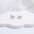 Macro shot of S925 sterling silver pink enamel bow stud earrings on a white tray - Pink Bowknot