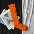 Vibrant orange ribbed knit long socks displayed on a modern black and white fabric base - Calf-length Vitality Orange