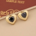 Macro shot of vintage heart studs with gold base and black gemstone on a gift box - Black