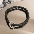 Close-up of black matte cylindrical beads with a polished silver metal ring buckle - Black/Matte Cylinder