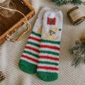 Dettaglio delle calze natalizie in pile con motivi festivi su un tappeto in maglia - Taglia unica / A righe