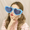 Close-up of a model wearing large blue heart-shaped party sunglasses for a cute stylish look - Blue