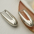 Orecchini a forma di spilla da balia in argento lucido su sfondo di lusso minimal - Argento
