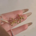 Elegant gold bow earrings made of premium alloy shown in hand for size perspective - Mini Bowknot Stud