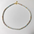 Detail of beaded natural stone necklace with cylindrical beads and gold heart clasp - Blue Red Brown Spotted