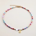 Detailed view of colorful beaded necklace with a white heart and golden letter B pendant - Letter B