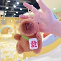 Brown capybara plush keychain with green strap and white lucky charm ornament - Dark Brown Red Fortune + Gold Clip