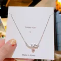 Collier élégant en acier titane avec pendentif cœur rose et détails de nœud en zircone - Cœur à nœud papillon argenté