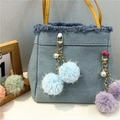 Detail of light blue denim tote bag with yellow handle and plush fur ball pendants - Sky Blue