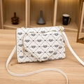 White monogram heart crossbody bag with gold hardware on a wooden table - White