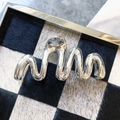 Detail of silver metallic hair claw clip with a wavy design on a checkered background - Wavy Streamline Style (4)