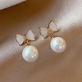 Detail of elegant gold bow earrings with white enamel inlay and hanging pearl drop - #13 Bow Pearl Earrings