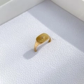 Detail van gouden zegelring met zonnestraalmotief en diamant op wit leer textuur - US 7 / Enkele Strass Stijl