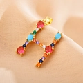 Close-up of golden letter H pendant set with vibrant multi-colored zircon gemstones - Letter H
