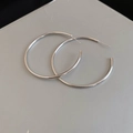 Macro shot of minimalist silver hoop earrings with high-polish finish and slender ear pins - 5cm / Silver / Silver Needle