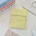 Detailed view of yellow quilted mini storage pouch with button closure on desk - Yellow