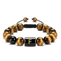 Detail of tiger eye stone beads bracelet with golden letter F on a black square bead - Letter F