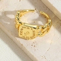Detalle del anillo de cadena de eslabones dorados con números romanos y sello cuadrado grabado - Anillo Geométrico de Números Romanos