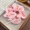 Detailed close-up of a pink ribbed knit scrunchie with a white ribbon bow in a wooden box - Pink Ribbed Knit Style