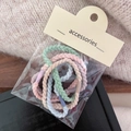 Detailed shot of multi-colored pastel elastic hair ties in transparent packaging - Braid Style
