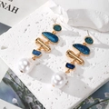Gold geometric glitter earrings with baroque pearls on a textured stone background - Blue