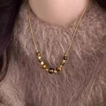 Tiger eye stone beaded necklace with gold chain shown on a brown plush sweater - Gradient Tiger Eye Bead Necklace (8# Necklace-Gold-Coffee)