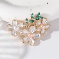 Elegante spilla a fiore con perle smaltate e cristalli verdi su ramo dorato di lusso - Bianco