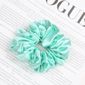 Chic mint green satin scrunchie with pleated texture on vintage magazine background - Teal