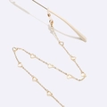 Detail of golden metal glasses chain featuring white heart charms and silicone loops - Heart