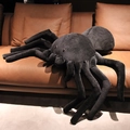 Grote zwarte spin knuffel van zacht materiaal op een bruine lederen bank als decoratie - 30x20cm / Zwart